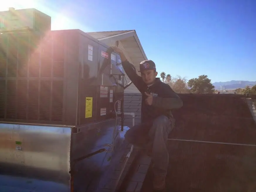 HVAC technician performing AC Tune-Up on a rooftop unit in Tupper Lake